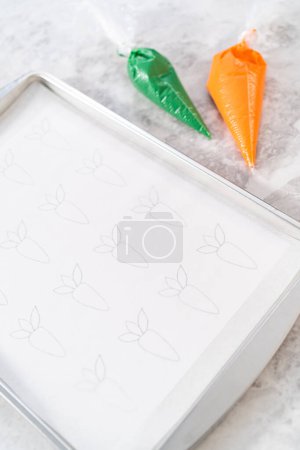 Foto de Tubería de chocolate derretido de una bolsa de tuberías sobre el papel de pergamino para hacer toppers pastel de zanahoria de chocolate. - Imagen libre de derechos