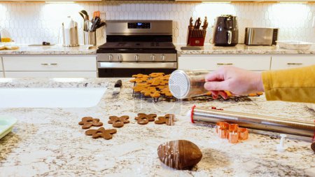 Photo for Using an adjustable rolling pin to roll out gingerbread cookie dough on the kitchen counter, getting ready for festive holiday baking. - Royalty Free Image