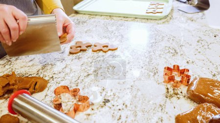 Téléchargez les photos : À l'aide de diverses coupeuses festives, découpaient de charmants biscuits au pain d'épice de la pâte roulée sur le comptoir en marbre élégant, apportant joie de vacances à la cuisine moderne. - en image libre de droit