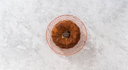 Téléchargez les photos : Flat lay. Removing freshly baked carrot bundt cake from the bundt cake pan to round the cooling rack. - en image libre de droit