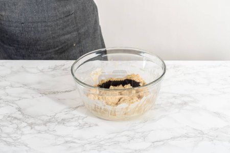 Téléchargez les photos : Mélanger les ingrédients secs et humides avec un fouet à la main dans un bol de mélange en verre pour cuire des muffins de graines de pavot citron. - en image libre de droit