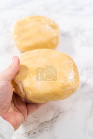 Téléchargez les photos : Emballage de pâte à biscuits dans une pellicule de cellophane à transférer au réfrigérateur pour le refroidissement. - en image libre de droit