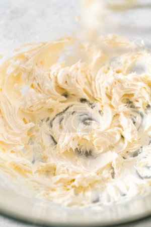 Photo for Mixing ingredients with a hand mixer in a large mixing bowl to make cream cheese frosting for carrot bundt cake. - Royalty Free Image