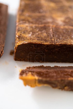 Photo for Cutting chocolate peanut butter fudge into small pieces on a white cutting board. - Royalty Free Image