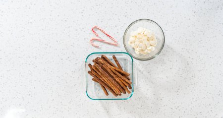 Téléchargez les photos : Pose plate. Ingrédients mesurés dans des bols à mélanger en verre pour fabriquer des tiges de bretzel recouvertes de chocolat de canne à sucre. - en image libre de droit