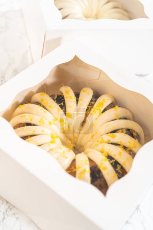 Photo for The freshly baked bundt cakes are carefully nestled into white paper boxes, preparing them for secure transportation while maintaining their delectable appearance. - Royalty Free Image