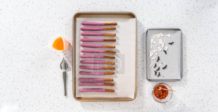 Photo for Flat lay. Dipping pretzel rods into melted chocolate to make Halloween chocolate-covered pretzel rods. - Royalty Free Image