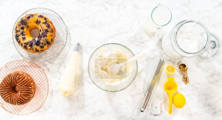 Téléchargez les photos : Pose plate. Combinez habilement les ingrédients à l'aide d'un mélangeur à main pour préparer un glaçage riche et lisse au fromage à la crème au beurre, parfait pour orner le gâteau bundt. - en image libre de droit