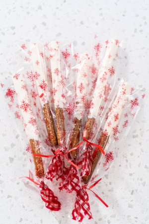 Téléchargez les photos : Emballage des tiges de bretzel recouvertes de chocolat de canne à bonbons maison dans des sacs en plastique transparent pour les cadeaux de Noël. - en image libre de droit