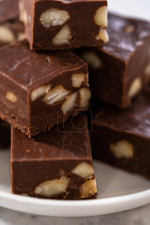 Photo for Homemade chocolate macadamia fudge square pieces on a white plate. - Royalty Free Image