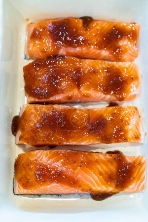 Foto de Hornear trozos de salmón fresco con salsa teriyaki en un plato cerámico seguro para horno. - Imagen libre de derechos
