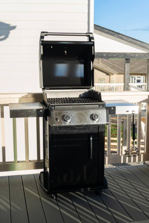 Photo for Sleek, open-lid, two-burner grill stands ready for use, conveniently positioned on the balcony of a suburban home, promising a delightful alfresco cooking experience. - Royalty Free Image
