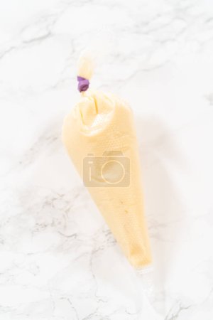 Téléchargez les photos : Remplissage de sacs de tuyauterie avec glaçage au fromage à la crème pour petits gâteaux roulés à la cannelle sans levure. - en image libre de droit