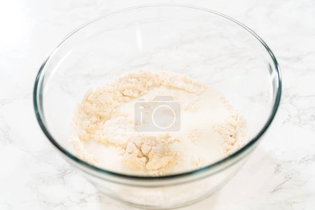 Foto de Mezclar ingredientes en un tazón de vidrio grande para hornear cupcakes de canela sin levadura. - Imagen libre de derechos