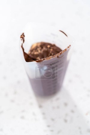 Téléchargez les photos : Melting chocolate chips in a candy melting pot to make chocolate-covered pretzel rods. - en image libre de droit