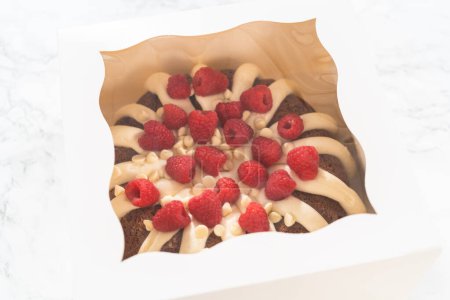 Foto de Con cuidado, el pastel de chocolate blanco de Raspberry Bundt se envasa en una caja de papel blanco, lista para regalar para brindar alegría e indulgencia a alguien especial. - Imagen libre de derechos
