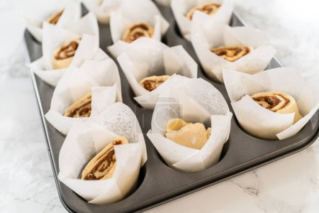 Photo for Filling cupcake liners with small cinnamon rolls to bake no-yeast cinnamon roll cupcakes. - Royalty Free Image