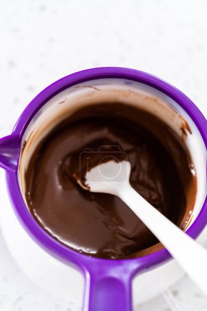 Foto de Melting chocolate chips in a candy melting pot to make chocolate-covered pretzel rods. - Imagen libre de derechos