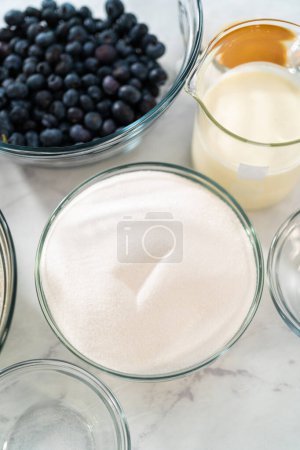 Photo for Measured ingredients in glass mixing bowls to bake lemon blueberry bundt cake. - Royalty Free Image