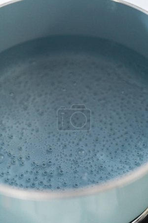 Foto de Boiling water in a cooking pot to prepare chocolate pistachio fudge. - Imagen libre de derechos