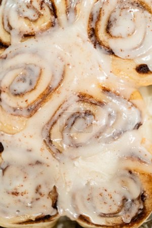 Photo for Just out of the oven, cinnamon rolls cool on a silicone baking mat, their icing glistening under the kitchen lights. - Royalty Free Image
