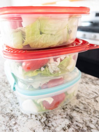 Foto de Envases llenos de ensalada y aderezo, preparados para la preparación conveniente de la comida a la hora del almuerzo. - Imagen libre de derechos