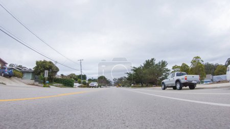 Photo for Santa Maria, California, USA-December 6, 2022-Vehicle navigates the streets of Morro Bay, California, during a cloudy winter day. The atmosphere is moody and serene as the overcast sky casts a soft - Royalty Free Image
