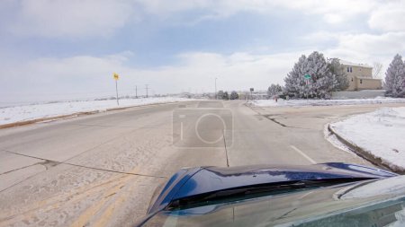 Photo for Traversing a freshly cleared, suburban road after a winter storm, one experiences a serene drive through an upscale residential neighborhood. Snow-covered houses and trees contribute to a picturesque - Royalty Free Image