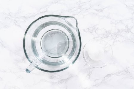 Foto de Los vasos medidores de vidrio están llenos de agua, alineados y listos para usarse en el lavado cuidadoso de fresas frescas, asegurando una limpieza precisa y exhaustiva.. - Imagen libre de derechos