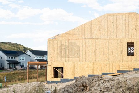 Foto de Un sitio de construcción en curso en los suburbios, con la etapa de encuadre de una casa unifamiliar. - Imagen libre de derechos