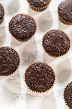 Téléchargez les photos : Cupcakes au chocolat fraîchement cuits sont prêts pour une transformation délicieuse car ils attendent un revêtement généreux de glaçage au chocolat riche et velouté. - en image libre de droit