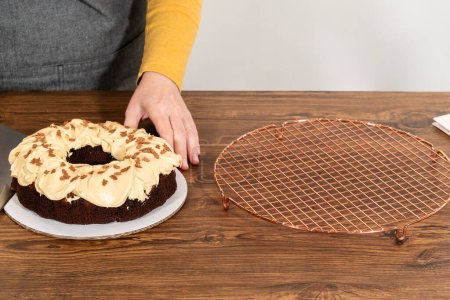 Téléchargez les photos : Placer soigneusement le gâteau bundt en pain d'épice, orné de glaçage au caramel salé et saupoudrer de pain d'épice, dans une boîte à gâteau bundt en papier blanc avec une fenêtre claire pour offrir. - en image libre de droit