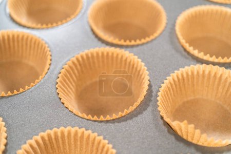 Photo for Getting ready to bake delicious chocolate cupcakes, we carefully line the cupcake pan with paper liners, ensuring a delightful treat awaits. - Royalty Free Image