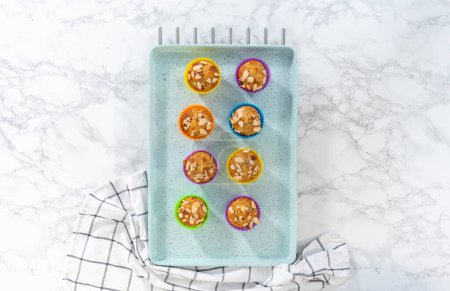 Photo for Flat lay. Freshly baked lemon poppy seed muffins garnished with almond slivers on the kitchen counter. - Royalty Free Image
