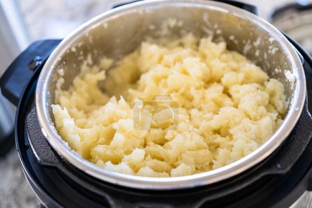 Téléchargez les photos : Dans une cuisine moderne et élégante, préparer des pommes de terre en purée veloutées à l'aide d'un autocuiseur pour un repas rapide et délicieux. - en image libre de droit