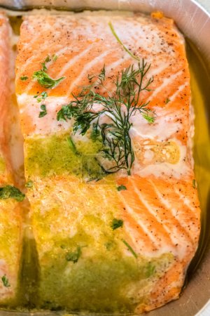 Foto de Descubre el delicioso viaje del salmón cocinado a la perfección en un horno, enclavado en una bandeja de papel de aluminio, adornado con mantequilla rica y especias tentadoras. - Imagen libre de derechos