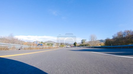 Téléchargez les photos : Par une belle journée d'hiver, une voiture parcourt l'emblématique Highway 1 près de San Luis Obispo, en Californie. Le paysage environnant est brunâtre et tamisé, avec des collines ondulantes et des zones côtières - en image libre de droit