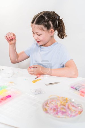 Photo for Little girl enjoys crafting colorful bracelets with vibrant clay beads set. - Royalty Free Image