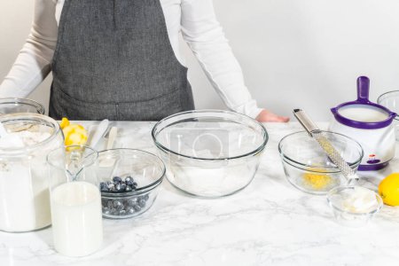 Foto de Integrar los ingredientes en un tazón de vidrio, revolviendo hábilmente con un batidor para elaborar un tentador pastel de limonero y arándano. - Imagen libre de derechos