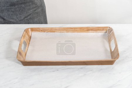Photo for Lining serving wood tray with parchment paper sheet to prepare a vegetarian party butter board for a party. - Royalty Free Image