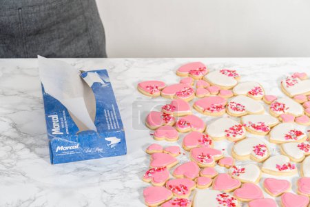 Téléchargez les photos : Denver, Colorado, États-Unis-9 février 2023-Stockage des biscuits au sucre en forme de coeur avec glaçage royal rose et blanc dans un grand récipient en plastique. - en image libre de droit