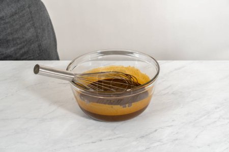 Foto de Mezclar ingredientes húmedos en un tazón de vidrio pequeño para hornear torta de pan de jengibre con relleno de caramelo - Imagen libre de derechos
