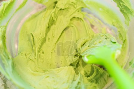 Téléchargez les photos : Dans une cuisine bien éclairée, un assortiment de glaçage à la crème au beurre dans différentes nuances de vert et d'autres couleurs est méticuleusement mélangé et préparé pour la décoration artistique de cupcakes de charme - en image libre de droit