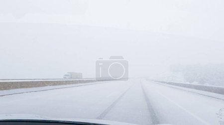 Photo for POV-Electric vehicle is captured deftly navigating the I-70 highway during a winter storm in Western Colorado. - Royalty Free Image