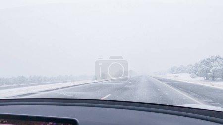 Photo for POV-Electric vehicle is captured deftly navigating the I-70 highway during a winter storm in Western Colorado. - Royalty Free Image