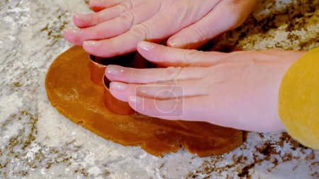 Téléchargez les photos : À l'aide de diverses coupeuses festives, découpaient de charmants biscuits au pain d'épice de la pâte roulée sur le comptoir en marbre élégant, apportant joie de vacances à la cuisine moderne. - en image libre de droit