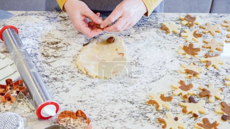 Téléchargez les photos : Utilisation d'un rouleau à pâtisserie réglable pour dérouler la pâte à biscuits au pain d'épice sur l'élégant comptoir en marbre dans une cuisine moderne, se préparer pour la cuisson de vacances festives. - en image libre de droit