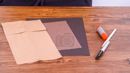 Téléchargez les photos : Pas à pas. L'enseignant guide la classe en ligne en fabriquant une marionnette en papier à partir d'un sac brun, en utilisant de manière créative une surface en bois comme espace de travail. - en image libre de droit