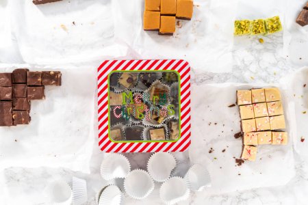 Photo for Flat lay. Packaging a homemade variety of fudge for Christmas food gifts into tin boxes. - Royalty Free Image