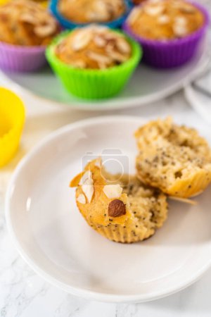 Foto de Magdalenas de semilla de amapola de limón recién horneadas adornadas con astillas de almendras en el mostrador de la cocina. - Imagen libre de derechos